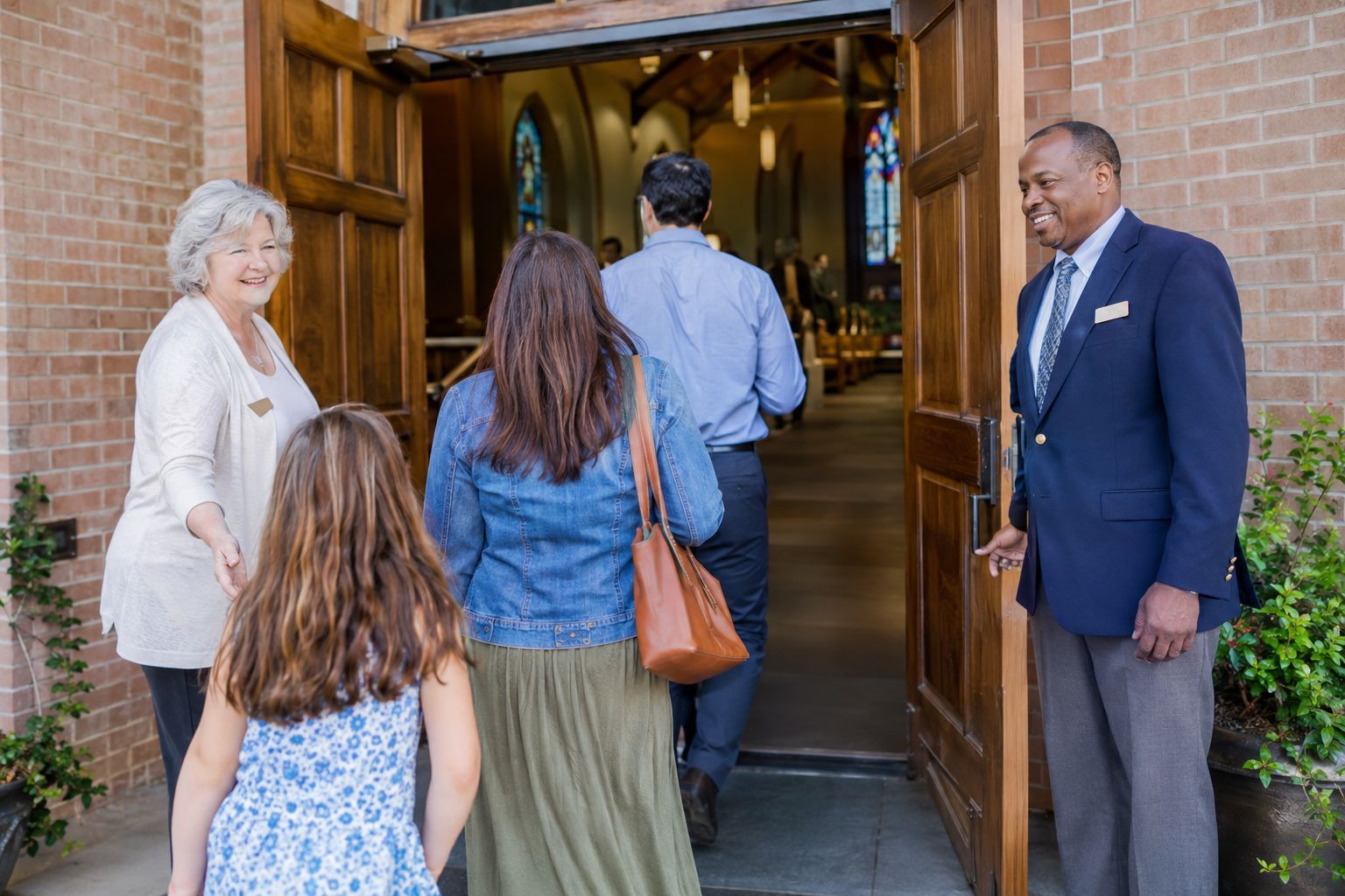Church greeters welcoming a family at the front doors.